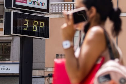 Una mujer pasa en Mallorca junto a un termómetro que muestra la temperatura en grados Celsius, el pasado agosto.