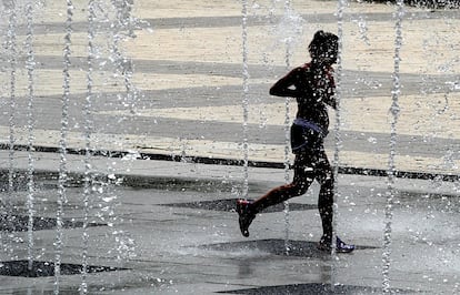 Alerta amarilla por calor entre las dos y las ocho de la tarde hoy en Madrid. En la imagen, una mujer corre entre las fuentes del parque Juan Carlos I de Madrid.