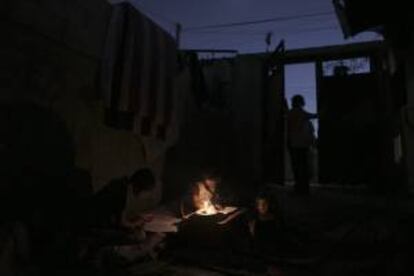 Una niña palestina lee a la luz de una vela dentro de la casa de su familia en Bait Lahiya, al norte de la Franja de Gaza. EFE/Archivo