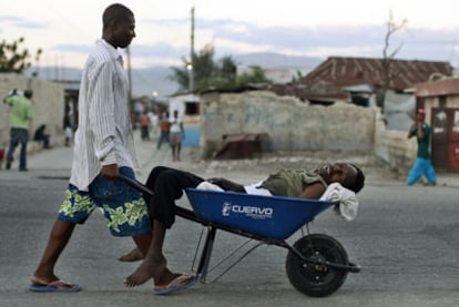 Un haitiano transporta a un enfermo con síntomas de cólera por el barrio de Cité Soleil, el viernes en Puerto Príncipe.