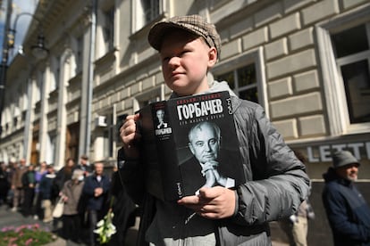 Un joven sostiene un libro con el retrato de Mijaíl Gorbachov mientras hace cola para asistir a la Casa de los Sindicatos de Moscú, este sábado.