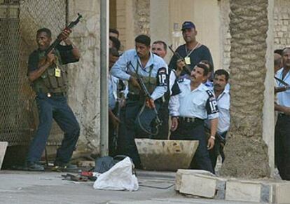 Policías iraquíes se parapetan cerca de un banco en Bagdad en el que habían entrado hombres armados.