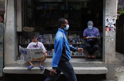 Dos hombres leen periódicos en una calle de Katmandú (Nepal). El Gobierno nepalí ha puesto fin a un encierro 120 días impuesto para controlar la pandemia de coronavirus.