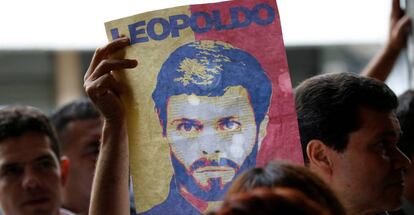 Un partidario de Leopoldo L&oacute;pez muestra un cartel con su rostro a las puertas de un tribunal de Caracas, el 20 de junio