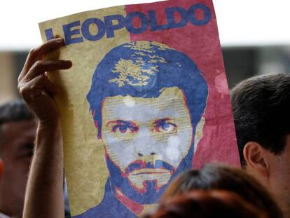 Un partidario de Leopoldo L&oacute;pez muestra un cartel con su rostro a las puertas de un tribunal de Caracas, el 20 de junio