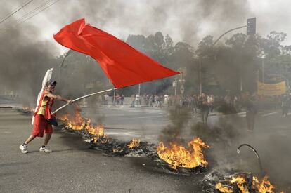 Un manifestante ondea una bandera roja tras una barricada de fuego, durante la protesta contra el presidente en funciones, Michel Temer, en Sao Paulo (Brasil).