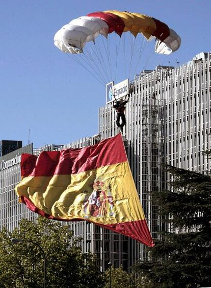 Un paracaidista con la bandera nacional desciende sobre el Paseo de la Castellana antes del comienzo del desfile militar del Día de la Fiesta Nacional que presiden hoy los Reyes en Madrid.