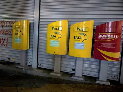 Dos hombres caminan frente a la oficina postal de Atenas, este lunes.