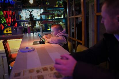 Roman, de 33 años, observa a su hijo Svyatoslav, de 6, jugar con la tablet en la barra del refugio improvisado para vecinos en la parte de abajo del restaurante Buena Vista Social Bar de Kiev