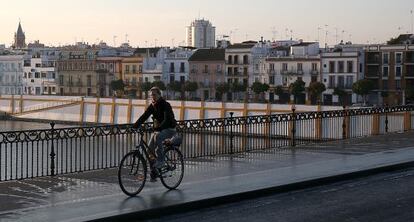 Un hombre cruza el puente de Triana por el carril bici, en Sevilla.