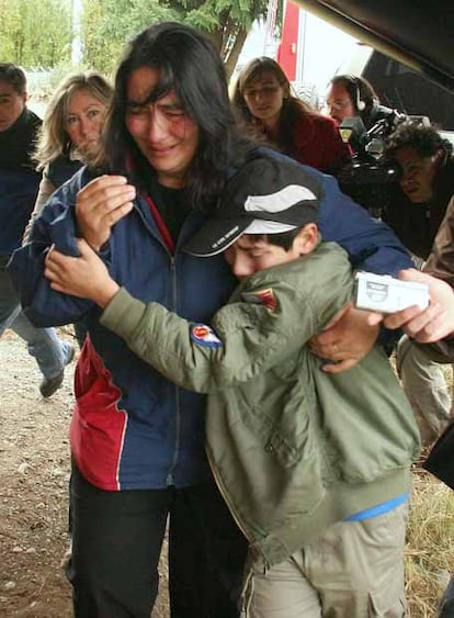 Maria Poblete hugs her son as she waits for the arrival of the body of her aunt, Elsa Poblete, in Puerto El esposo de Elsa Poblete se había acercado al mar el día sábado, cuando olas de más de 6 metros lo arrastraron dentro, junto a su pequeño nieto de dos años.