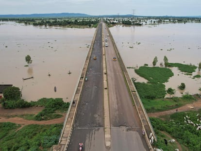 En esta vista aérea tomada el 25 de septiembre de 2022, los residentes locales cruzan el puente Numan mientras conducen hacia un terreno más seguro, lejos de las inundaciones en Numan, estado de Adamawa, al noreste de Nigeria.