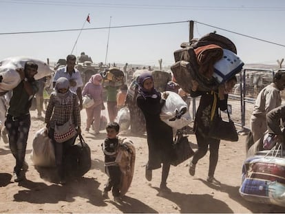 Refugiados kurdos sirios cruzan hacia Turquía desde Siria, cerca de la ciudad de Kobani, en 2014.