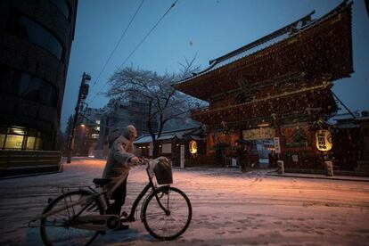 Más de 100 vuelos nacionales e internacionales fueron cancelados hoy, después de que en la víspera más de 300 vuelos con destino sobre todo a los aeropuertos del área capitalina se vieran afectados por las fuertes nevadas. En la imagen, un hombre camina con su bicicleta en Tokio (Japón), el 22 de enero de 2018.