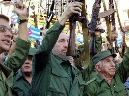 El presidente de Cuba, Fidel Castro (centro), levanta un fusil AK-47 durante la ceremonia de celebración de los 40 años de socialismo en la isla.