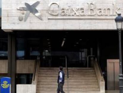 Un hombre observa el logo de Caixabank que desde ayer sustituye al de Bankia, tras la fusión de ambos bancos.