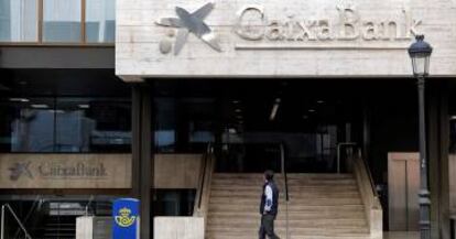 Un hombre observa el logo de Caixabank que desde ayer sustituye al de Bankia, tras la fusión de ambos bancos.