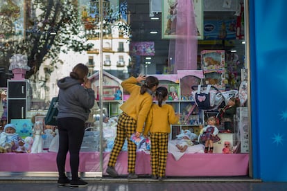 Dos menores miran el escaparate de una tienda de juguetes en Sevilla.