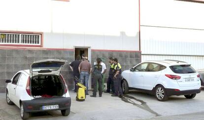 Varias personas, entre ellas agentes de la Guardia Civil, observan el interior de la nave, donde fue hallado el cuerpo.