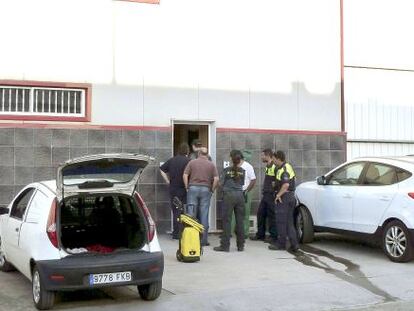 Varias personas, entre ellas agentes de la Guardia Civil, observan el interior de la nave, donde fue hallado el cuerpo.