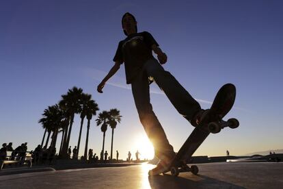 Un joven practica con su patín mientras atardece en el Skatepark de Venice Beach.