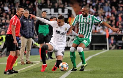 El delantero del Valencia, Rodrigo, cae en la disputa del balón con el defensa del Betis, Sidnei Rechel Da Silva.