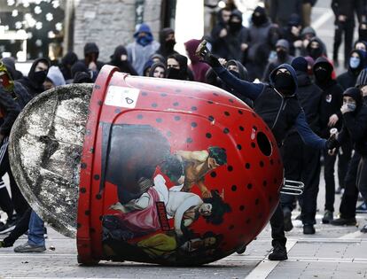 Un jovén lanza una piedra tras un contenedor en la calle Mercaderes de Pamplona (Navarra) durante una jornada de protestas convocada por la organización Ikasle Abertzaleak en la que se han producido enfrentamientos con la Policía Nacional.