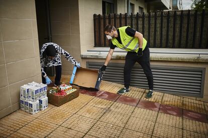 Dos voluntarios reparten comida del banco de alimentos, esta mañana en Nuevo Artica, cerca de Pamplona.