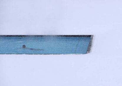 Un hombre nada en una piscina exterior rodeada de nieve, en Bischofshofen (Austria).