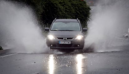 A car drives through a flooded street in Valencia.