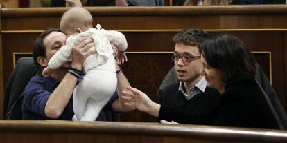El líder de Podemos, Pablo Iglesias, coge a la hija de la diputada de su partido Carolina Bescansa, en presencia del diputado íñigo Errejón.