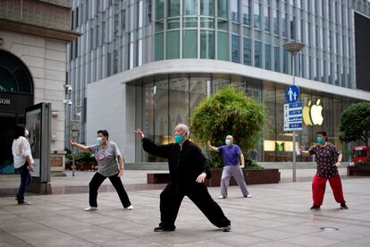 Un grupo de personas practica 'tai chi' en una calle comercial de Shanghái, este miércoles.  La pasada noche, la ciudad financiera celebraba con fuegos artificiales y un ambiente digno del Año Nuevo que se ponía fin al estricto confinamiento.