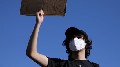 Um manifestante com uma máscara com os dizeres “não consigo respirar” segura um cartaz que faz menção aos 8 minutos e 46 segundos.