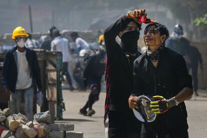 Un manifestante vierte Coca-Cola en el rostro de un compañero para disminuir los efectos del gas lacrimógeno durante una represión de las fuerzas de seguridad en una manifestación en Yangon (Myanmar). El miedo al arresto y las torturas de los militares han empujado a una veintena de periodistas a abandonar el país, sumergido en un apagón informativo que en pocas semanas ha aniquilado los últimos periódicos independientes impresos y empujado a los reporteros a una vida casi clandestina.