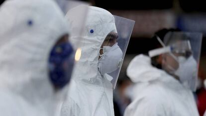 Varios trabajadores de un mercado colombiano llevan trajes y máscaras protectoras.