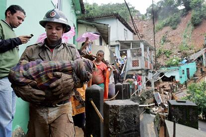 Un bombero transporta el cadáver de un niño víctima de un corrimiento de tierras en la favela Borel de Río de Janeiro.