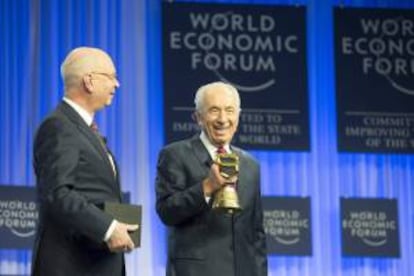 El presidente israelí, Simón Peres (dcha) recibe un cencerro suizo de manos del fundador y presidente del Foro Económico Mundial de Davos, el alemán Klaus Schwab (izda), en el Foro Económico de Davos celebrado hoy, viernes 24 de enero de 2014 en Davos (Suiza).