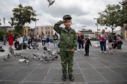 Una niña vestida con el uniforme del Ejercito Mexicano posa para la cámara.