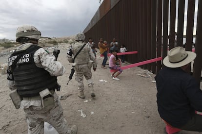 Miembros de la policía militar mexicana patrullan entre los niños y los adultos que acuden a la valla fronteriza para jugar, en Ciudad Juárez.