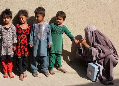 Una trabajadora sanitaria marca el dedo de una niña con tinta tras vacunarle de la polio en Kandahar (Afganistán).