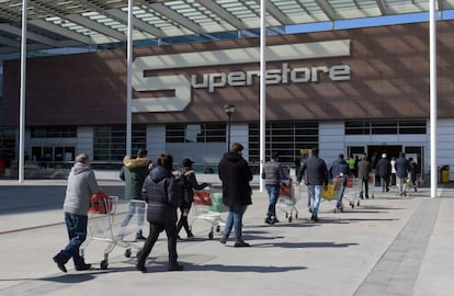 Los consumidores hacen cola a la entrada de un supermercado en Milán para abastecerse, tras el anuncio del Gobierno italiano de aislar el norte de Italia ante la amenaza del coronavirus.