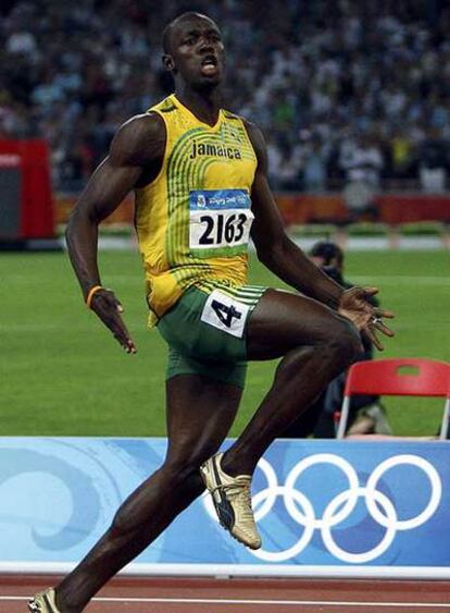 Usain Bolt cruza la línea de meta de los 100 metros celebrando su triunfo.