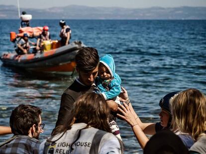 Un migrante con su bebé, ayudado a su llegada de la isla griega de Lesbos, el pasado lunes.