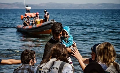 Un migrante con su bebé, ayudado a su llegada de la isla griega de Lesbos, el pasado lunes.