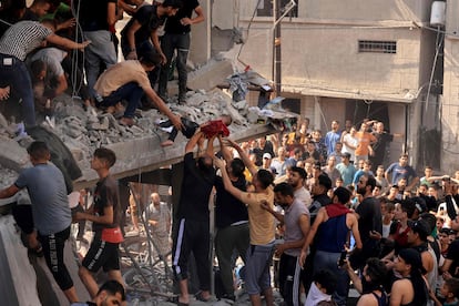 Hombres palestinos rescatan a un niño de entre los escombros, este martes en Jan Yunis.  