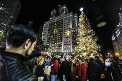 Este año se ha vuelto a celebrar el encendido de alumbrado en la calle y con público, después que el año pasado el Ayuntamiento organizó este acto en un formato ‘virtual’, desde el palacio de Cibeles. En la foto, un grupo de jóvenes posa delante del abeto de Plaza de España, con el hotel RIU de fondo.