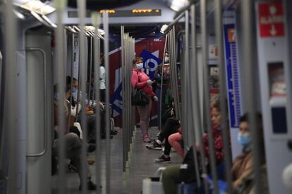 Varios viajeros en el interior de un vagón del metro de Madrid.