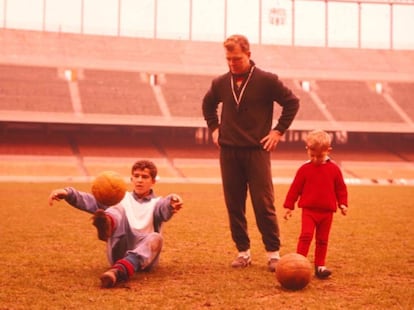 Ladislao Kubala con su hijos Branko (sentado) y Carlos (de rojo) en el césped del Camp Nou en 1960.