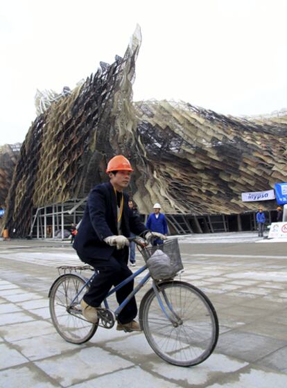 Un obrero chino pasa en bicicleta delante de la plaza del pabellón de España en la Expo 2010 de Shanghai