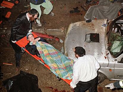 Dos hombres sacan a una mujer herida del escenario del atentado, en el barrio de Mea Shearim, en Jerusalén.